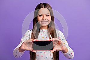 Photo portrait of girl holding phone with blank space with two hands isolated on bright purple colored background