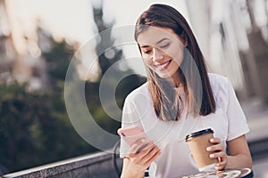 Photo portrait of girl holding phone paper cup smiling outdoors