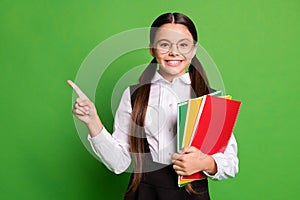 Photo portrait of girl pointing finger at copyspace isolated on vivid green colored background