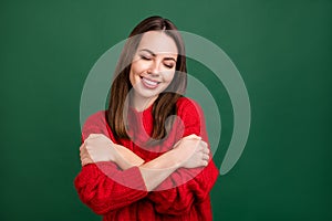 Photo portrait girl in red pullover dreamy embracing herself smiling isolated green color background
