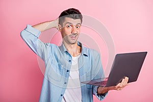 Photo portrait of grimacing student working laptop unsure uncertain wearing casual shirt isolated pastel pink color