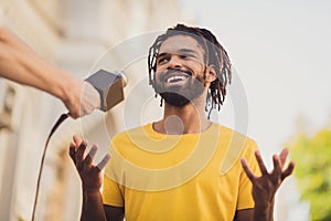 Photo portrait of guy with dreadlocks smiling talking to reporter taking part in public asking speaking in microphone