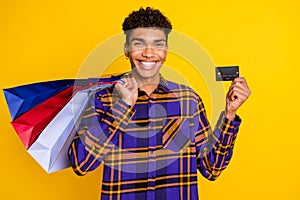 Photo portrait of guy showing v-sign keeping bargains showing bank card isolated on vibrant yellow color background