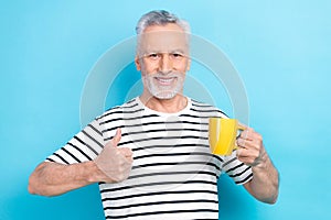 Photo portrait of handsome grandad hold coffee tea mug cup show thumb up dressed stylish striped clothes isolated on