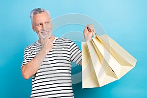 Photo portrait of handsome grandad hold shopping bags thoughtful wear trendy striped clothes isolated on blue color