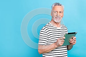 Photo portrait of handsome grandad hold tablet look empty space wear trendy striped clothes isolated on blue color