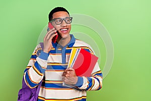 Photo portrait of handsome young guy talk phone modern student manuals dressed stylish striped outfit isolated on green