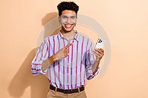 Photo portrait of handsome young male finger point hold gadget wear trendy striped formalwear outfit isolated on beige