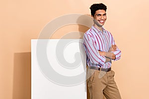 Photo portrait of handsome young male folded arms white poster wear trendy striped formalwear outfit isolated on beige