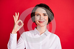 Photo portrait of happy business woman showing okay gesture smiling in formal wear isolated bright red color background