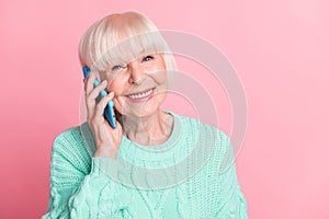 Photo portrait of happy grandmother smiling talking on mobile phone communicating isolated on pastel pink color