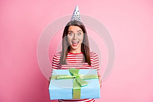 Photo portrait of happy surprised girl receiving wrapped present wearing festive cap smiling isolated on pastel pink