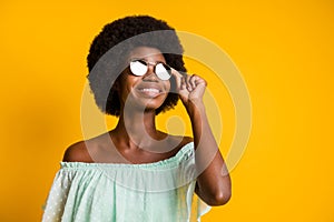 Photo portrait of hopeful woman touching glasses isolated on vivid yellow colored background