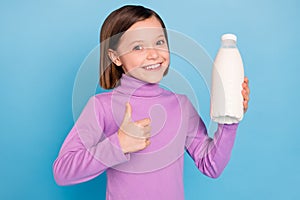 Photo portrait little girl smiling keeping bottle with milk showing thumb up gesture isolated pastel blue color