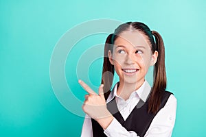 Photo portrait little girl in uniform showing finger empty space dreamy isolated pastel turquoise color background