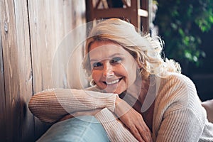 Photo portrait of lovely retired woman sit sofa cheerful smile dressed casual outfit cozy home interior living room in