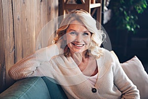 Photo portrait of lovely retired woman sit sofa have rest smile dressed casual outfit cozy home interior living room in