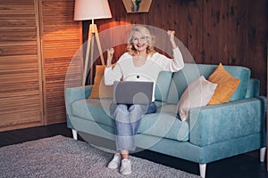 Photo portrait of lovely retired woman sit sofa netbook celebrate dressed casual outfit cozy home interior living room