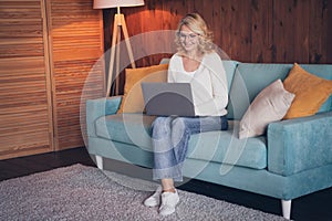 Photo portrait of lovely retired woman sit sofa work remotely dressed casual outfit cozy home interior living room in