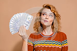 Photo portrait of lovely young lady hold look interested money dollars dressed stylish striped garment isolated on beige