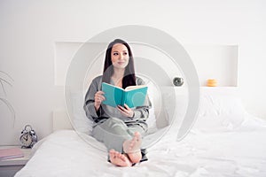 Photo portrait of lovely young lady sit bed read book minded dressed stylish gray sleepwear  on white bedroom