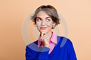 Photo portrait of lovely young lady touch chin look minded empty space dressed stylish blue garment isolated on beige