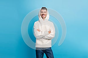 Photo portrait of man with folded arms wearing wool hoodie isolated on pastel blue colored background