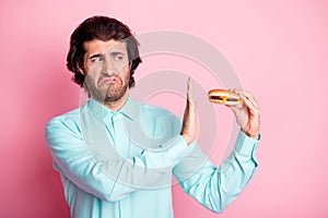 Photo portrait of man refusing to eat disgusting cheeseburger isolated on pastel pink colored background