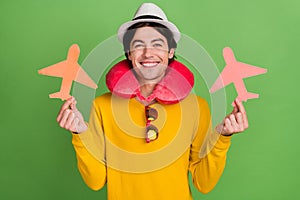 Photo portrait man smiling wearing neck pillow showing paper planes isolated pastel green color background