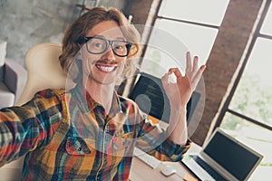 Photo portrait man wearing glasses taking selfie working on computer coding showing okay sign smiling