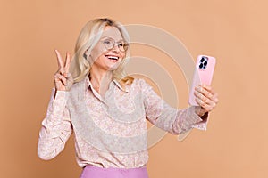Photo portrait of nice retired female take selfie show v-sign wear trendy formalwear isolated on beige color background