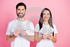 Photo portrait of nice young couple hold money banknotes fan dollars wear trendy white clothes isolated on pink color