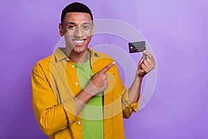 Photo portrait of nice young guy holding point credit card bank ecommerce dressed stylish yellow look isolated on violet