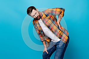 Photo portrait of nice young guy touch back need painkiller wear trendy plaid garment isolated on blue color background