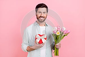 Photo portrait of nice young male bouquet boyfriend tulips 8 march candy box wear trendy blue garment isolated on pink