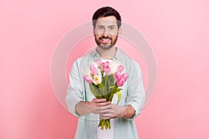 Photo portrait of nice young male hold bouquet tulips boyfriend 8 march wear trendy blue garment isolated on pink color