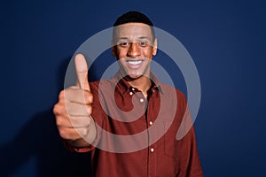 Photo portrait of nice young man approve show thumb up wear trendy brown outfit isolated on dark blue color background