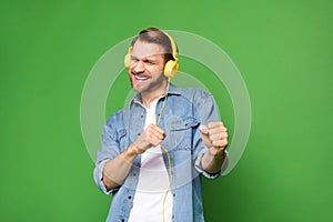 Photo portrait of overjoyed man listening music wearing earphones in casual clothes isolated bright green color