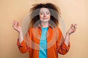 Photo portrait of pretty young girl closed eyes om gesture meditation wear trendy orange outfit isolated on beige color