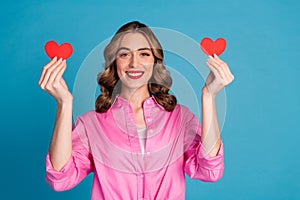 Photo portrait of pretty young girl hold two little heart postcards wear trendy pink outfit hairdo isolated on blue