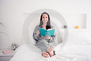 Photo portrait of pretty young girl sit bed read book have rest wear trendy gray nightwear isolated on comfortable