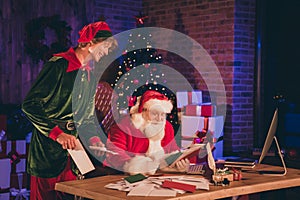 Photo portrait of santa claus and elf reading letters from kids