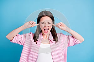 Photo portrait of screaming woman closing ears with fingers isolated on pastel blue colored background