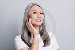 Photo portrait of senior woman with grey hair touching cheek wearing white t-shirt smiling isolated on grey color photo