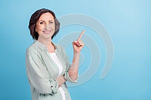 Photo portrait senior woman smiling pointing finger blank space isolated pastel blue color background