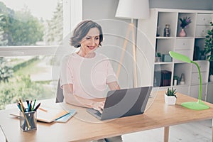 Photo portrait senior woman typing message sitting at table working on laptop at home