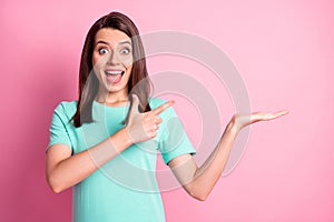 Photo portrait of shocked surprised girl pointing with finger holding empty space on palm staring isolated on pastel