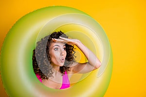Photo portrait of shocked woman looking far ahead with hand at forehead through inflatable green ring wearing pink