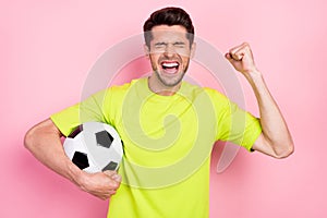 Photo portrait shouting man wearing bright t-shirt keeping soccer ball gesturing like winner isolated pastel pink color