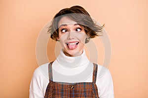 Photo portrait of silly fooling grimacing girl showing tongue isolated on pastel beige color background